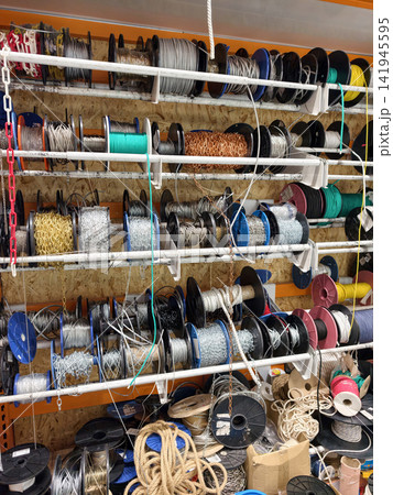 Ropes cables and chains arranged in structured coils and bobbins on store shelves in a construction market supplying durable equipment for lifting Ropes cables and chains arranged in structured coils and bobbins on store shelves in a construction market supplying durable equipment for lifting 141945595
