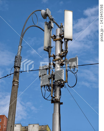 A cellular communication tower mounted on a low pole, standing next to a roadside streetlight A cellular communication tower mounted on a low pole, standing next to a roadside streetlight 141945598