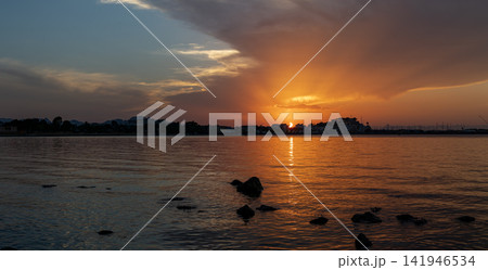 Coastal panorama in Denia shows solar eclipse as sun sets behind Denia Castle with clouds and sea in view Coastal panorama in Denia shows solar eclipse as sun sets behind Denia Castle with clouds and sea in view 141946534