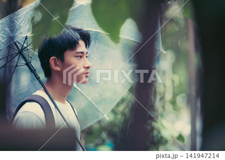 雨の日に透明傘をさして遠くを見つめる男子中学生 雨の日に透明傘をさして遠くを見つめる男子中学生 141947214
