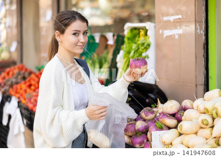 Girl shopper choosing ripe radish at street market 141947608