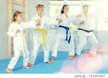 Preteen girl in kimono practicing punches as part of kata during family training 141947807