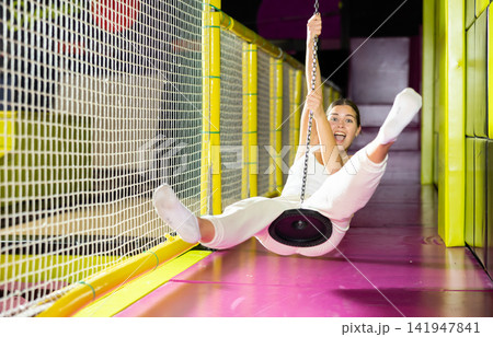 Happy girl goes down zip line at high speed in an amusement park. Storm of emotions and delight Happy girl goes down zip line at high speed in an amusement park. Storm of emotions and delight 141947841