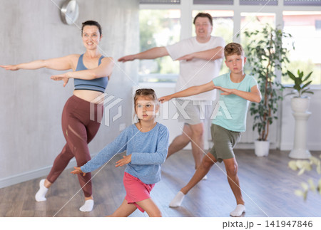 Cute little girl practicing dance movements with her family members Cute little girl practicing dance movements with her family members 141947846