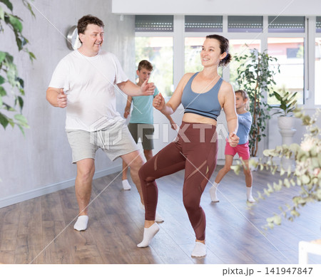 Happy middle-aged man and woman practicing dance in pairs together with their children Happy middle-aged man and woman practicing dance in pairs together with their children 141947847