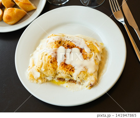 Portion of cannelloni with minced beef, covered with sauce, served on table in restaurant Portion of cannelloni with minced beef, covered with sauce, served on table in restaurant 141947865