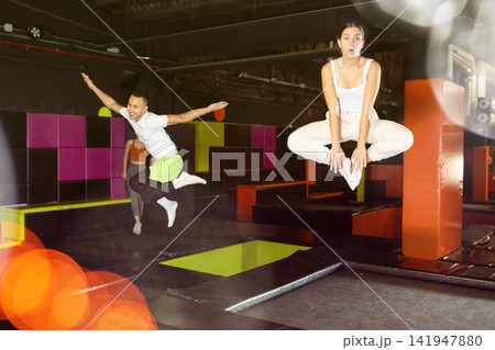 Happy girl bouncing on trampoline in indoor amusement park Happy girl bouncing on trampoline in indoor amusement park 141947880