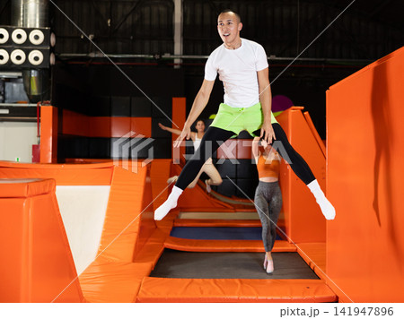 Male athlete training to jump on trampolines at trampoline center 141947896