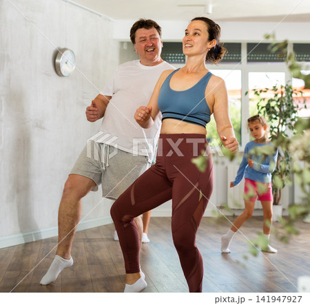 Happy middle-aged man and woman practicing dance in pairs together with their children Happy middle-aged man and woman practicing dance in pairs together with their children 141947927