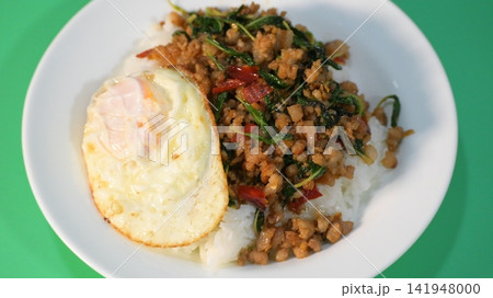 stir fried pork with holy basil on top with fried egg on cooked rice 141948000