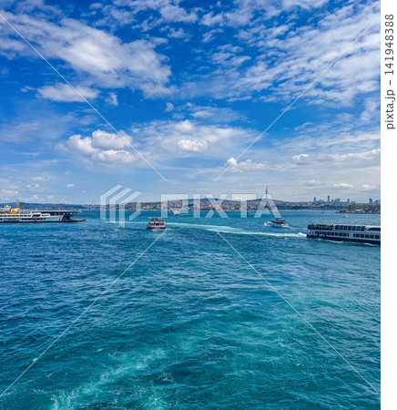 Ferries and boats cross the turquoise Bosphorus Strait with Istanbul's skyline and Camlica Tower visible in the distance.. High quality photo 141948388