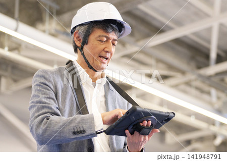 建設現場でタブレットを使って作業内容を確認する日本人男性 建設現場でタブレットを使って作業内容を確認する日本人男性 141948791