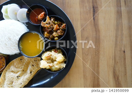 Indian Bengali meal platter with rice dal vegetable curry and salad on a black plate Indian Bengali meal platter with rice dal vegetable curry and salad on a black plate 141950099