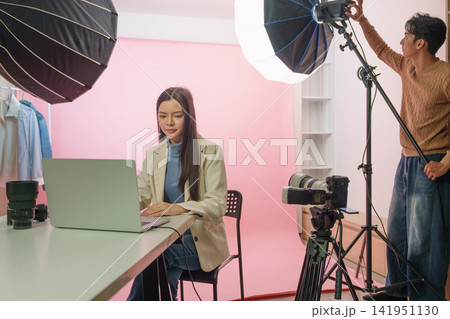 Asian photographer and crew adjusting lighting equipment in modern studio for photo shoot Asian photographer and crew adjusting lighting equipment in modern studio for photo shoot 141951130