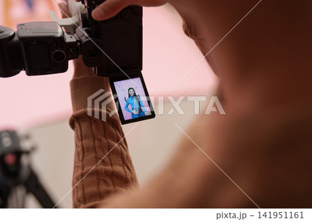 Photographer viewing model on camera LCD screen during studio shoot Photographer viewing model on camera LCD screen during studio shoot 141951161