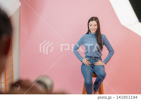 Asian female model posing during photo studio shoot against pink background Asian female model posing during photo studio shoot against pink background 141951194