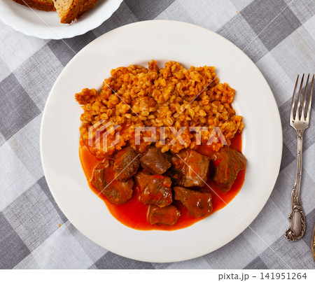 There is portion of hearty food on plate - pearl barley with beef stew in tomato sauce There is portion of hearty food on plate - pearl barley with beef stew in tomato sauce 141951264