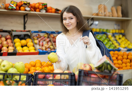 Girl choosing ripe apples in grocery supermarket Girl choosing ripe apples in grocery supermarket 141951295