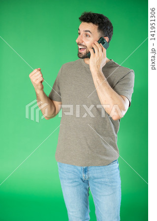 Adult man talking on mobile phone in front of green screen Adult man talking on mobile phone in front of green screen 141951306