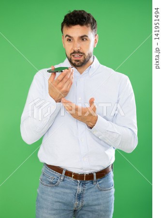 Adult man recording voice message in front of green screen Adult man recording voice message in front of green screen 141951494