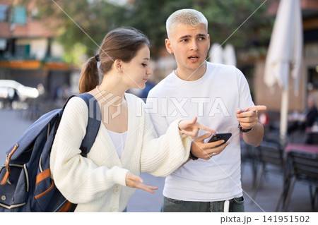 Couple walking around the city and looking at a map on mobile Couple walking around the city and looking at a map on mobile 141951502