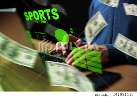 A person engages in sports betting online while handling cash in a dark setting 141951510