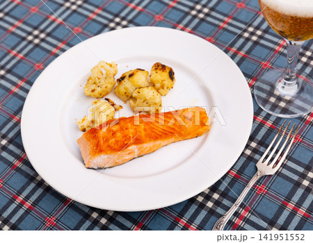 On plate there is piece of fried salmon fillet and vegetable side dish, deep-fried cauliflower 141951552