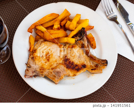 Fried pork chops with bone, supplemented with slices of French fries Fried pork chops with bone, supplemented with slices of French fries 141951561