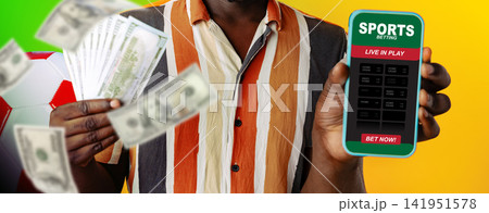 Man holding cash and a smartphone with sports betting app during a game Man holding cash and a smartphone with sports betting app during a game 141951578