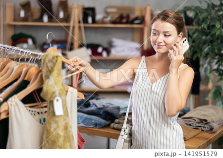 Young woman talking on phone in clothing store Young woman talking on phone in clothing store 141951579