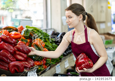 Young saleswoman laying out red pepper paprika in the store 141951675