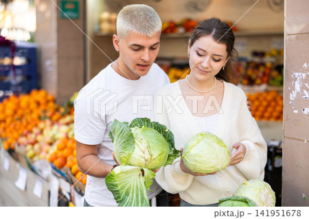 Young couple standing in the market and choosing vegetables Young couple standing in the market and choosing vegetables 141951678