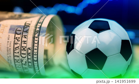Sport betting with cash and a soccer ball on a table during an event Sport betting with cash and a soccer ball on a table during an event 141951699