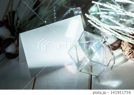 Blank card beside glass ornament and winter decorations on wooden surface Blank card beside glass ornament and winter decorations on wooden surface 141951759