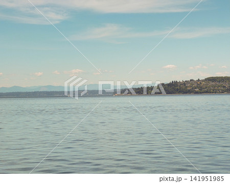 Wide panoramic view of the calm blue sea and distant hills under a soft summer sky at Point Ruston. Wide panoramic view of the calm blue sea and distant hills under a soft summer sky at Point Ruston. 141951985