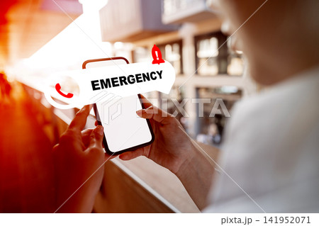 Emergency service call is made from a mobile phone during an urgent situation in a busy public space 141952071