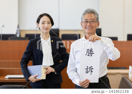 法廷で勝訴の書を掲げる依頼人と女性弁護士 法廷で勝訴の書を掲げる依頼人と女性弁護士 141952139