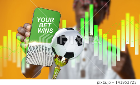 Sports betting success displayed on a mobile phone with a soccer ball in focus Sports betting success displayed on a mobile phone with a soccer ball in focus 141952725