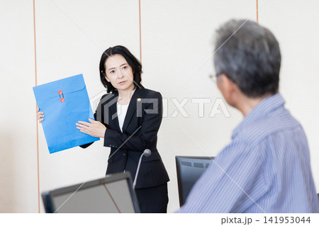 法廷で証拠書類を提示し証人尋問を行う女性弁護士 法廷で証拠書類を提示し証人尋問を行う女性弁護士 141953044
