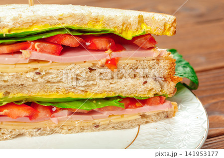 Close up of delicious looking sandwich with tomato and ham filling Close up of delicious looking sandwich with tomato and ham filling 141953177