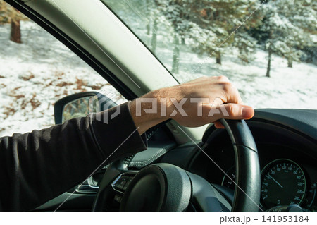 Winter travel. Driver maintains control on snowy road while wearing winter gear Winter travel. Driver maintains control on snowy road while wearing winter gear 141953184