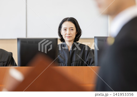 法廷で審理を行う女性裁判官と弁論する弁護士 法廷で審理を行う女性裁判官と弁論する弁護士 141953356