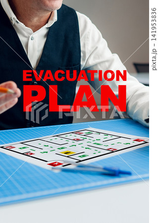 Evacuation plan being discussed at a table with a printed layout and a person holding a pen Evacuation plan being discussed at a table with a printed layout and a person holding a pen 141953836