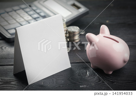 Savings and financial planning with a piggy bank, blank card, and calculator on a table 141954033