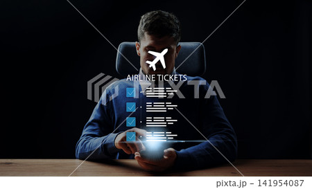 Booking airline tickets online from a mobile device in a dark setting while checking flight details and itinerary Booking airline tickets online from a mobile device in a dark setting while checking flight details and itinerary 141954087