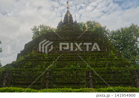Faith shrouded in green lush grass and moss of Buddhist pagoda at Wat Tham Pla in Northern Thailand Faith shrouded in green lush grass and moss of Buddhist pagoda at Wat Tham Pla in Northern Thailand 141954900