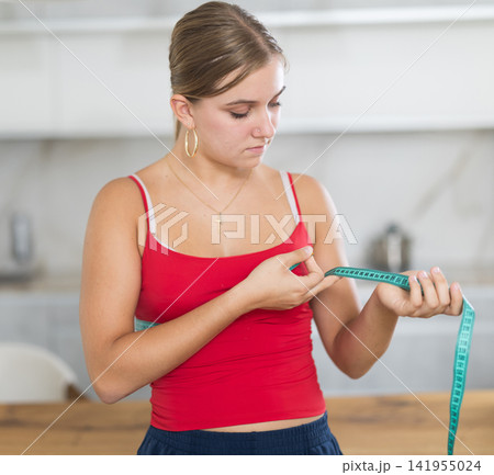 Teenage girl measures her body with centimeter 141955024