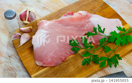 Preparation of raw pork cinch parsley and garlic on wooden board Preparation of raw pork cinch parsley and garlic on wooden board 141955055