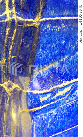 Closeup of polished blue lapis lazuli stone with gold pyrite veining, layered mineral bands, granular texture, and reflective surface under bright directional light Closeup of polished blue lapis lazuli stone with gold pyrite veining, layered mineral bands, granular texture, and reflective surface under bright directional light 141955649