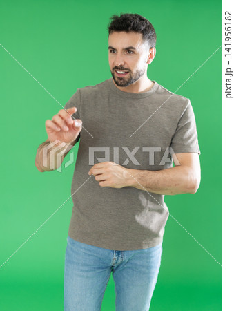 Adult man using virtual screen in front of green screen Adult man using virtual screen in front of green screen 141956182